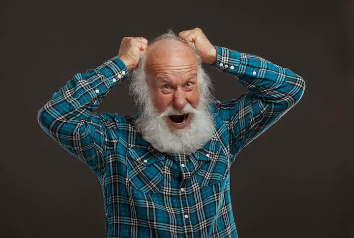 Viejo barbudo enfadado tirándose del pelo