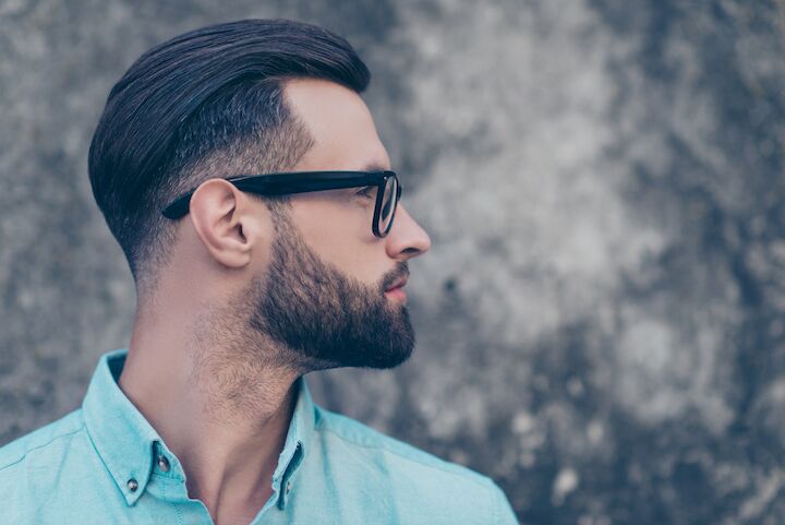 Hombre con barba corta y pelo peinado hacia atrás con gafas
